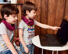 Zwei Kinder schauen auf einen Computer.