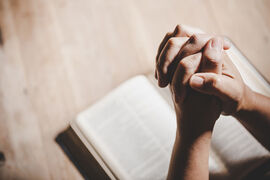 Hände zum Gebet gefaltet über einer Bibel